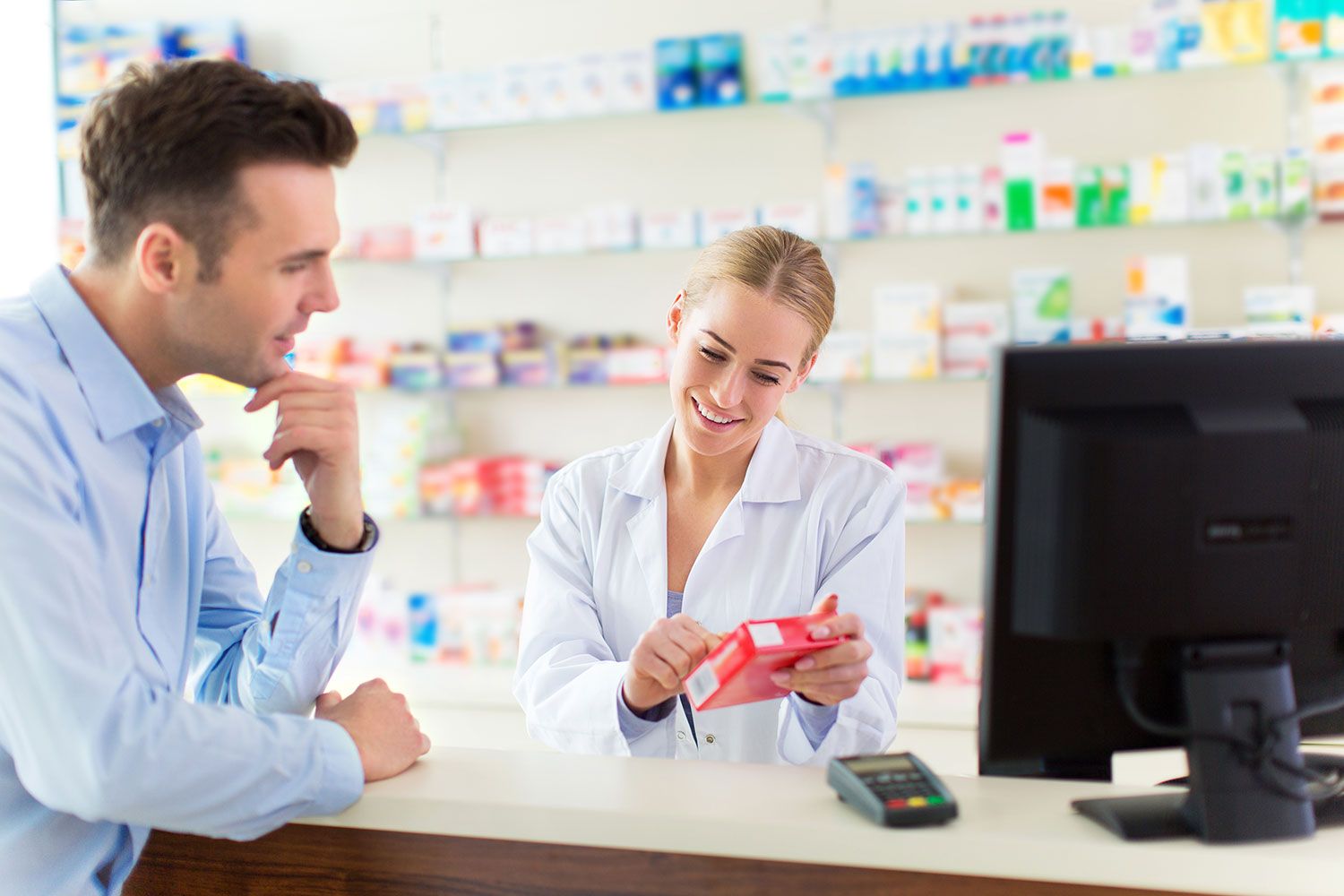 Eine Apothekerin berät einen Kunden, der sein vorbestelltes Medikament abholt